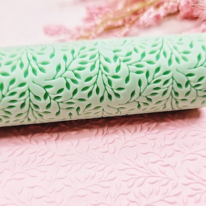 May include: A green rolling pin with a leaf pattern. The rolling pin is used to create an embossed design on fondant or dough.