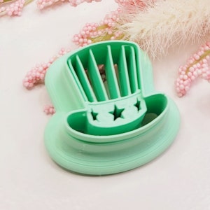 Könnte beinhalten: Ein grüner Plastik-Ausstecher in Form eines Zylinders mit Sternen und Streifen.