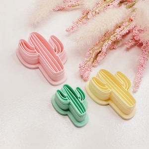 Puede incluir: Tres cortadores de galletas de plástico en capas con forma de cactus en rosa, amarillo y verde.