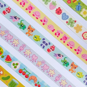Puede incluir: Una colecci&oacute;n de cintas washi coloridas con varios patrones. Los dise&ntilde;os incluyen animales de dibujos animados, frutas, flores y alimentos. Las cintas est&aacute;n dispuestas en diagonal, mostrando una variedad de colores e ilustraciones.