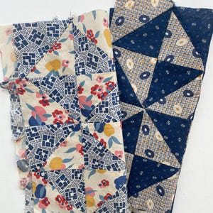 May include: Two fabric pieces with patchwork designs. One has a cream background with blue geometric shapes and red, yellow, and blue floral patterns. The other features a navy blue and tan geometric pattern with white and yellow circular shapes.