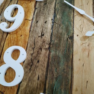 May include: Close-up of a wooden clock face with white numbers 8 and 9. The clock hands are white and point to the right.