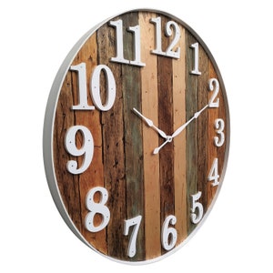 May include: A round wooden clock with white Roman numeral hour markers and white hands. The clock face is made of reclaimed wood planks in various shades of brown, beige, and blue.