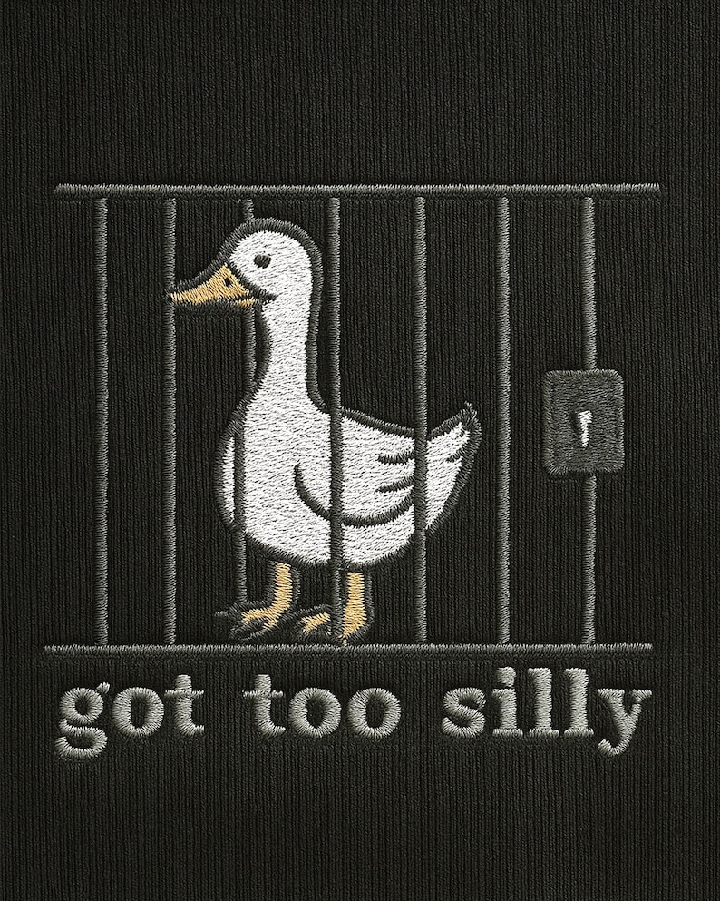 K&ouml;nnte beinhalten: Schwarzer Stoff mit einem gestickten Design, das eine wei&szlig;e Ente in einem K&auml;fig zeigt. Die Ente hat einen gelben Schnabel und gelbe F&uuml;&szlig;e. Der Text "got too silly" ist unter dem K&auml;fig gestickt.
