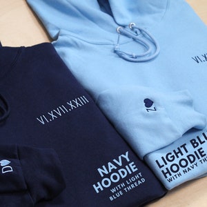 Personalized anniversary hoodie pictured. Perfect for one year anniversary gifts for boyfriend, for husband, men. Navy hoodie with light blue embroidery on the left. Light blue hoodie with navy embroidery on the right. Wedding gift example pictured.