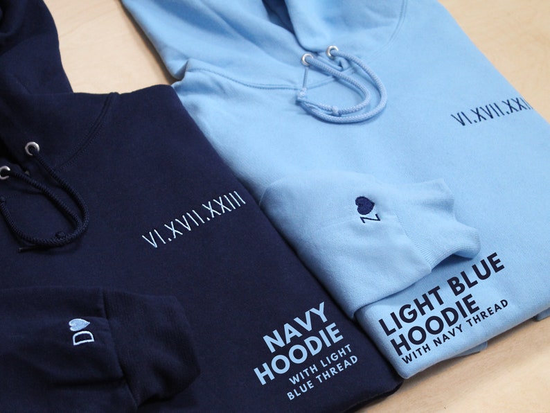 Personalized anniversary hoodie pictured. Perfect for one year anniversary gifts for boyfriend, for husband, men. Navy hoodie with light blue embroidery on the left. Light blue hoodie with navy embroidery on the right. Wedding gift example pictured.