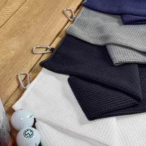 Peut inclure: Un ensemble de six serviettes de golf de diff&eacute;rentes couleurs, dont le blanc, le gris, le noir et le bleu. Chaque serviette a une texture gaufr&eacute; et un mousqueton pour une fixation facile &agrave; un sac de golf.