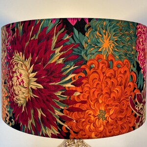 May include: A lampshade with a floral print featuring large, vibrant red, orange, and green chrysanthemums on a black background.