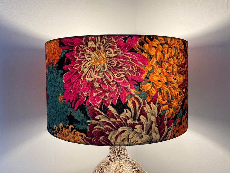 May include: A lampshade with a floral pattern in shades of pink, orange, teal, and cream. The flowers are stylized and resemble chrysanthemums.