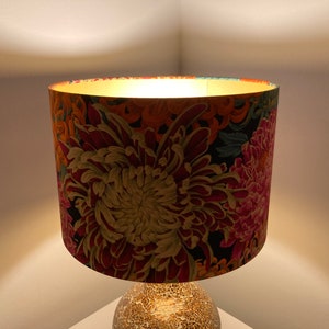 May include: A lampshade with a floral pattern featuring large pink, red, and yellow flowers on a black background.
