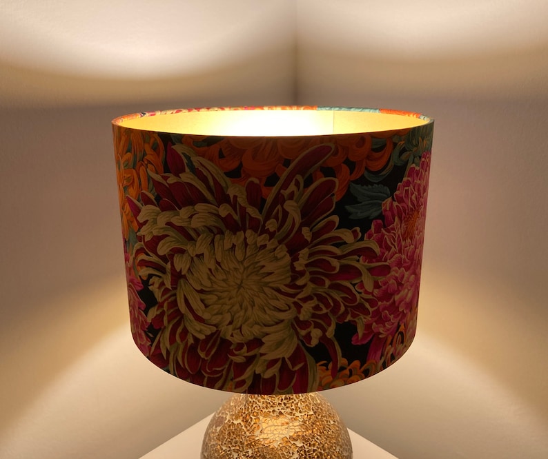 May include: A lampshade with a floral pattern featuring large pink, red, and yellow flowers on a black background.