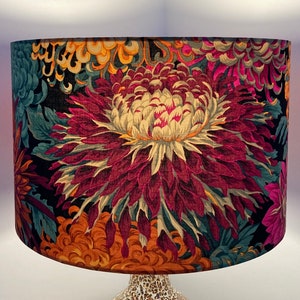 May include: A black lampshade with a floral pattern featuring large, vibrant pink, yellow, and orange flowers on a dark background.