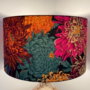 May include: A black lampshade with a floral pattern featuring large pink, orange, and teal flowers. The flowers are stylized and have a vintage feel.