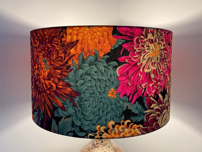 May include: A black lampshade with a floral pattern featuring large pink, orange, and teal flowers. The flowers are stylized and have a vintage feel.