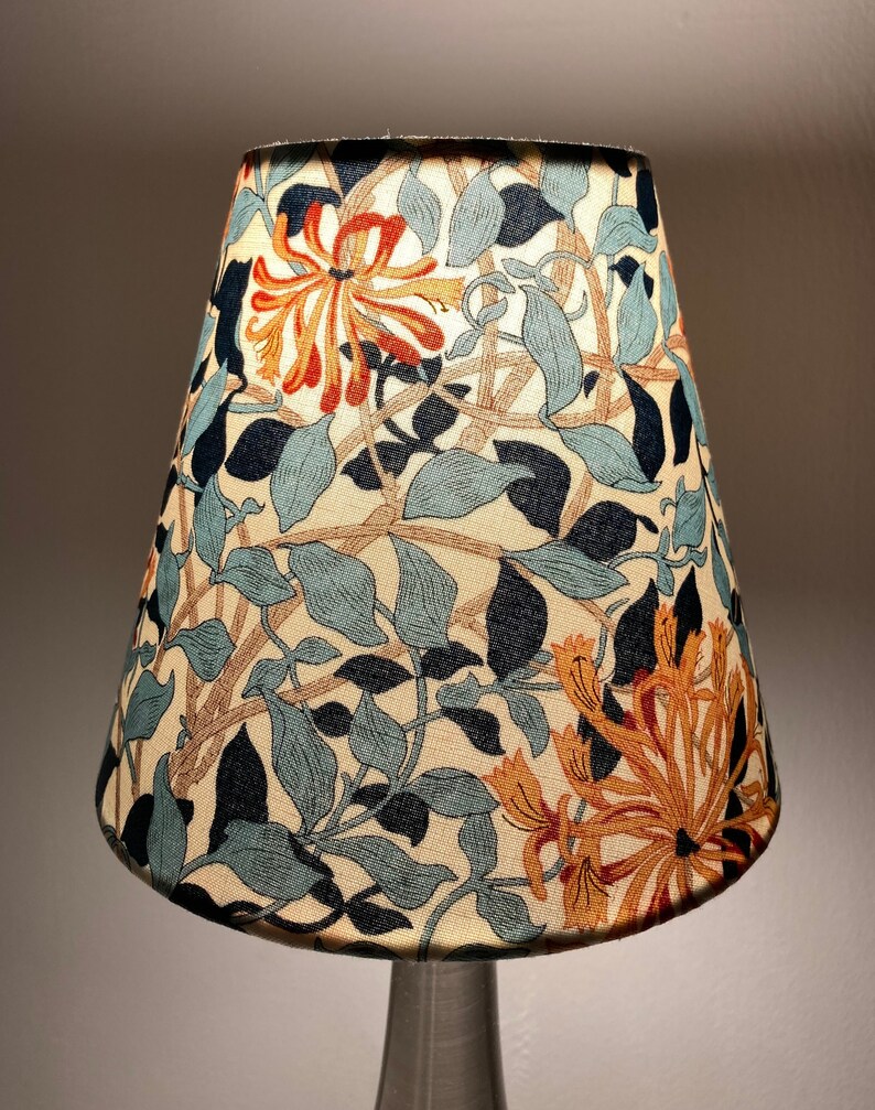 May include: A lampshade with a floral pattern featuring blue, green, orange, and brown hues. The pattern is reminiscent of honeysuckle vines.