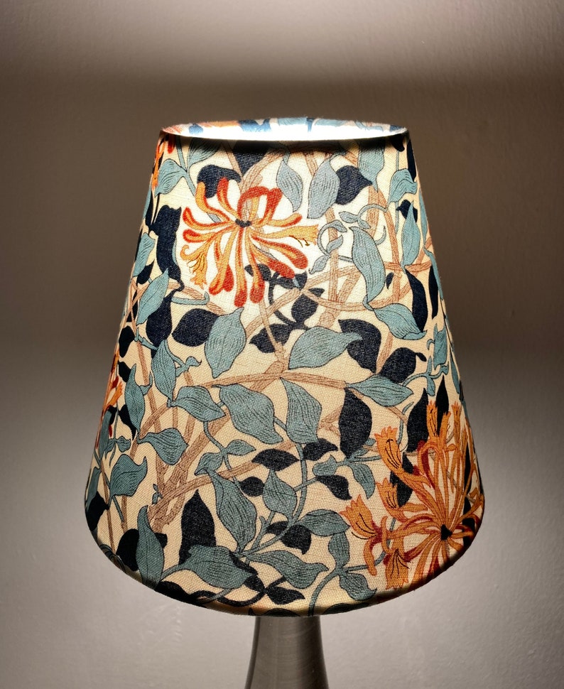 May include: A lampshade with a floral pattern featuring orange, blue, and green flowers on a cream background.