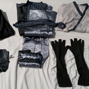 May include: A set of costume accessories including a long, silver-grey satin robe, a black satin sash, a pair of black fingerless gloves, a black pouch, a black skirt, and a silver-grey satin headband.