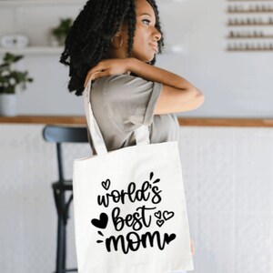 May include: White tote bag with black text that reads "world's best mom" with small hearts around the text.