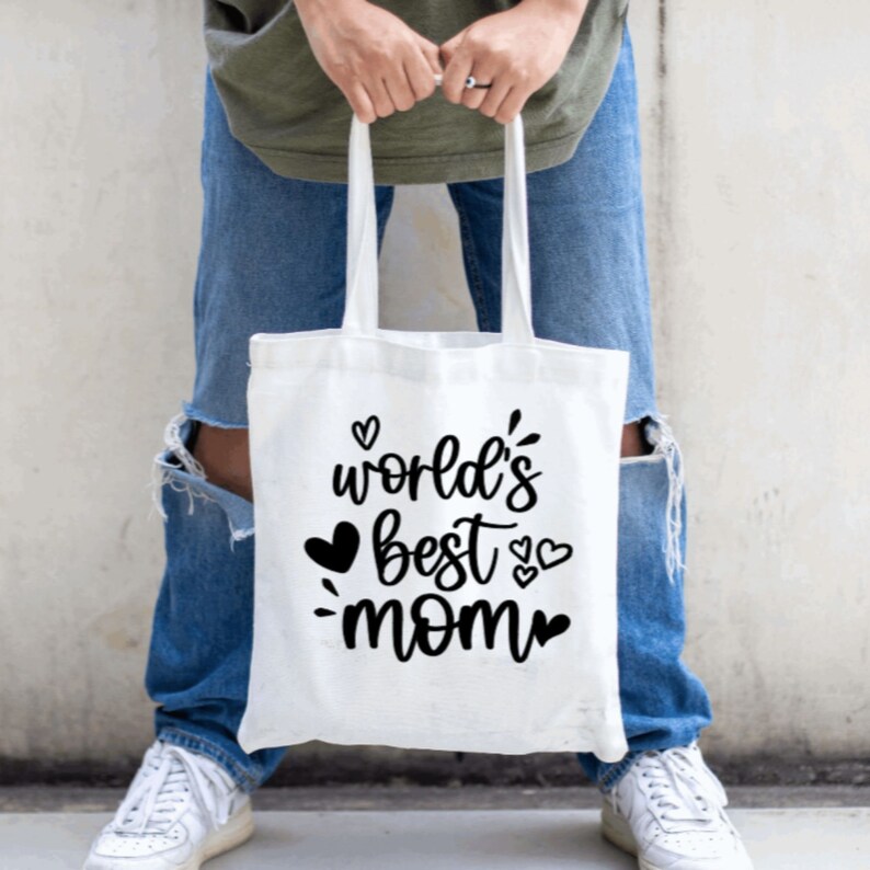 May include: White tote bag with black text that reads "world's best mom" with hearts around the text.