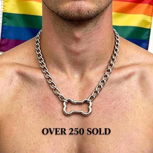 May include: A silver-toned metal chain necklace featuring a central bone-shaped pendant. The necklace is displayed against a background with a rainbow flag. The text "OVER 250 SOLD" is printed in black below the pendant on the image.