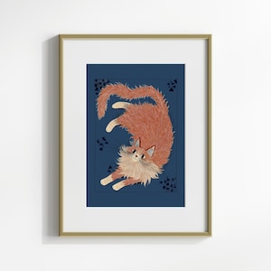 May include: Framed art print featuring a stylized illustration of a fluffy orange cat against a dark blue background. The cat is depicted in a playful pose, with its tail curved and paws extended. The artwork is framed in a gold-colored frame.