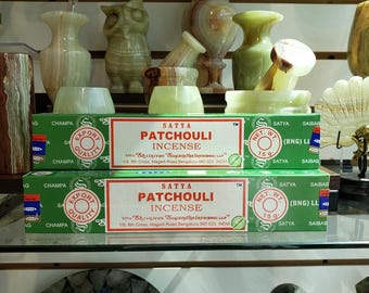 Può includere: Esposizione di articoli per la casa in onice verde e bianco, tra cui vasi, ciotole e una statuina di gufo. Due scatole di incenso Satya Patchouli sono in primo piano. Le scatole sono verdi con testo rosso e bianco.