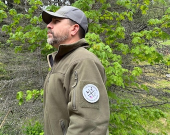 May include: An olive green fleece jacket with a gray cap. The jacket has a patch on the sleeve with the text "THE OHIO PREPPER" and a graphic. The jacket has a zipper closure and multiple pockets.