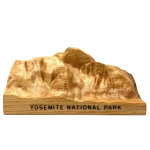 May include: A wooden model of a mountain range with the text "Yosemite National Park" engraved on the base.