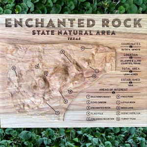 Carte topographique de la zone naturelle de l'État d'Enchanted Rock, sculptée dans un bloc de bois massif, avec des détails sur le parc et des caractéristiques remarquables