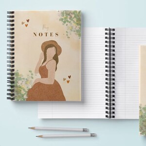 May include: Two spiral bound notebooks with watercolor designs. The front cover of the first notebook features a woman in a brown dress and hat with the text "My Notes". The front cover of the second notebook features a watercolor design with the text "Be kind to yourself".