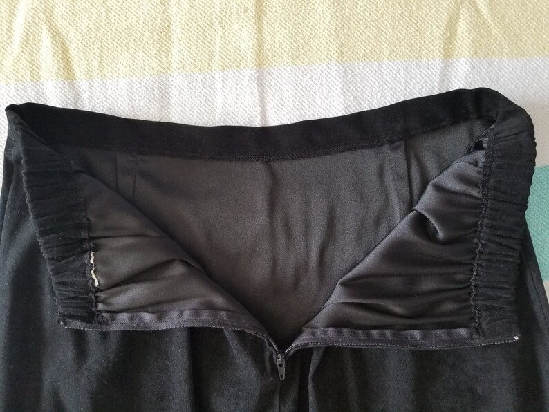 May include: Black skirt with a zipper closure and a black elastic waistband.