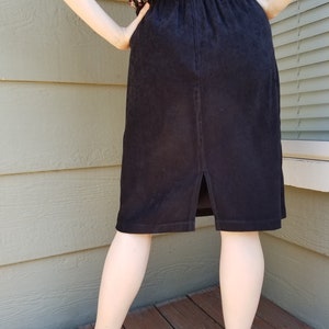 May include: A black corduroy skirt with a back slit and an elastic waistband.