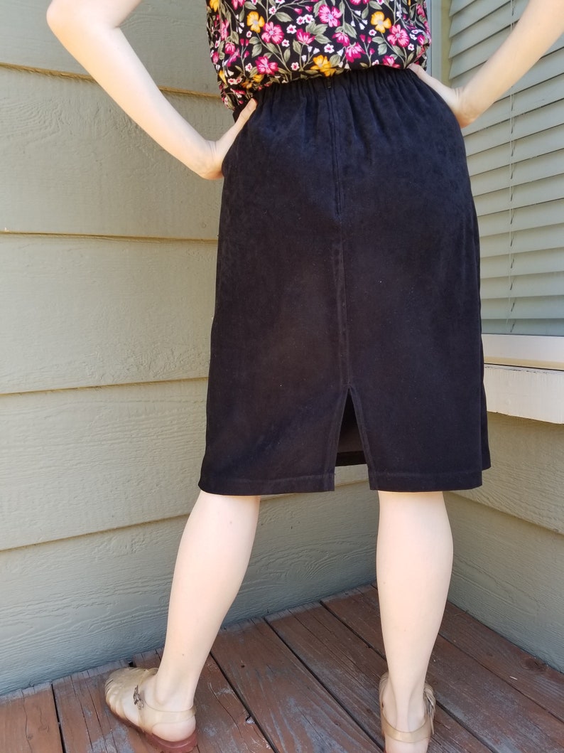May include: A black corduroy skirt with a back slit and an elastic waistband.