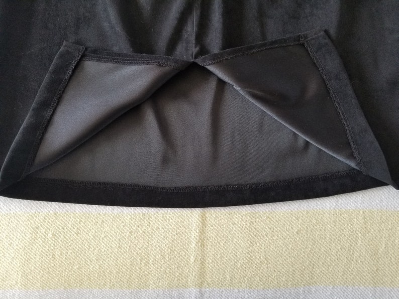May include: Black velvet skirt with a black lining and a black hem. The skirt is turned inside out to show the lining.