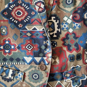 May include: A brown, blue, red, and white patterned blazer with a single button closure. The blazer has a pocket on each side.