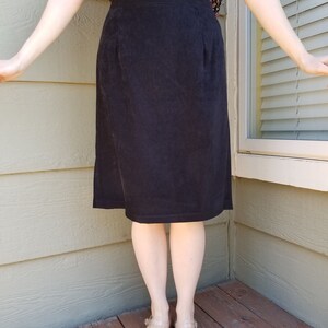 May include: A black corduroy skirt with a straight silhouette. The skirt is knee-length and has a simple design.