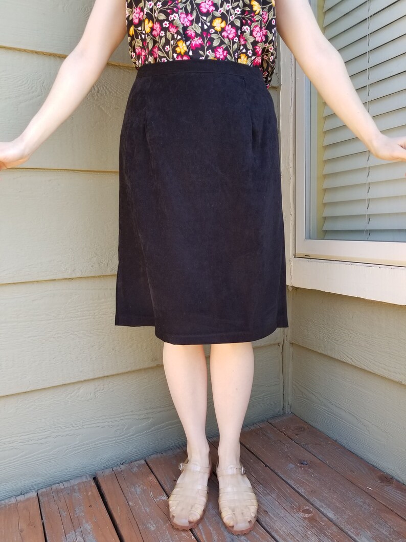 May include: A black corduroy skirt with a straight silhouette. The skirt is knee-length and has a simple design.