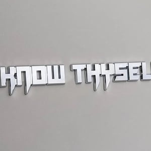 May include: A silver metal sign with the words "KNOW THYSELF" in a bold, stylized font.