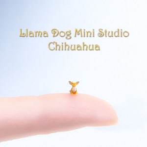 May include: A small, yellow chihuahua figurine sitting on a finger. The figurine is made of polymer clay and has a white chest and ears. The text "Llama Dog Mini Studio Chihuahua" is visible above the figurine.