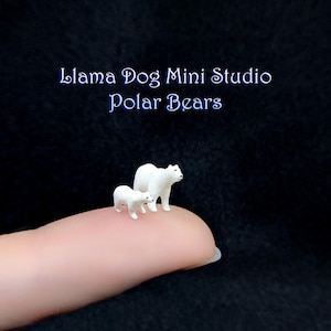 May include: Two miniature white polar bears, one adult and one cub, standing on a finger. The image is captioned "Llama Dog Mini Studio Polar Bears."