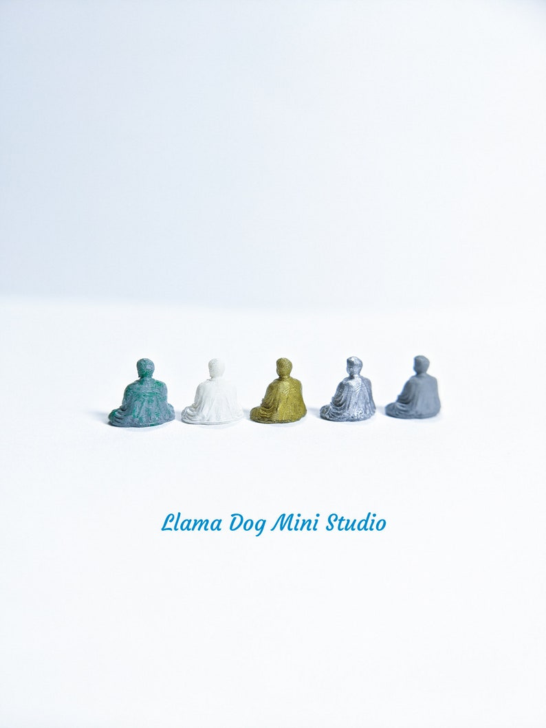 May include: Five miniature seated figures in different colours: teal, white, gold, silver, and grey. The figures are arranged in a row on a white surface. The text "Llama Dog Mini Studio" is printed below the figures.