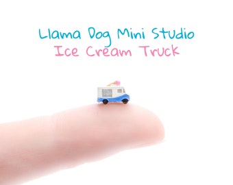 May include: A miniature blue and white ice cream truck with a pink ice cream cone on top, sitting on a finger.