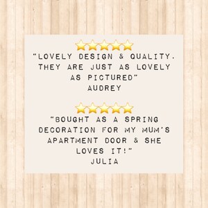 Two customer reviews with five star ratings. The first review reads 'LOVELY DESIGN & QUALITY. THEY ARE JUST AS LOVELY AS PICTURED' AUDREY. The second review reads 'BOUGHT AS A SPRING DECORATION FOR MY MUM'S APARTMENT DOOR & SHE LOVES IT!' JULIA.