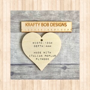A wooden heart-shaped decoration with the text 'WIDTH: 12CM', 'DEPTH: 4MM', 'MADE WITH', 'ITALIAN POPLAR PLYWOOD'.
