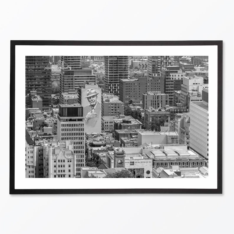 Puede incluir: Una fotograf&iacute;a a&eacute;rea en blanco y negro de un horizonte urbano con una gran valla publicitaria que presenta a un hombre con un sombrero. La valla publicitaria est&aacute; en el lado de un edificio en el medio de la imagen. La ciudad est&aacute; llena de edificios altos y la foto est&aacute; tomada desde un &aacute;ngulo alto.
