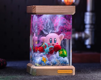 May include: A pink and white character figurine with a blue and green butterfly inside a clear resin lamp with a wooden base. The lamp has a pink and white swirl design and the text "WOODANDRESINVN" on the base.