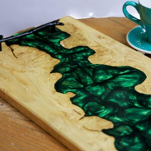May include: A wooden serving tray with a dark green epoxy resin inlay. The tray has a black metal handle.