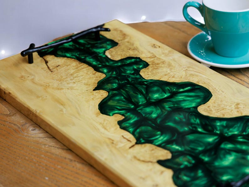 May include: A wooden serving tray with a dark green epoxy resin inlay. The tray has a black metal handle.