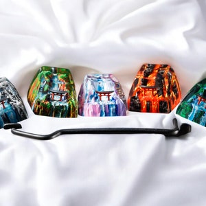 K&ouml;nnte beinhalten: F&uuml;nf bunte Harz-Keycaps mit einem japanischen Tempeldesign. Jede Keycap hat ein anderes Farbschema, darunter Blau, Gr&uuml;n, Lila, Orange und Schwarz.