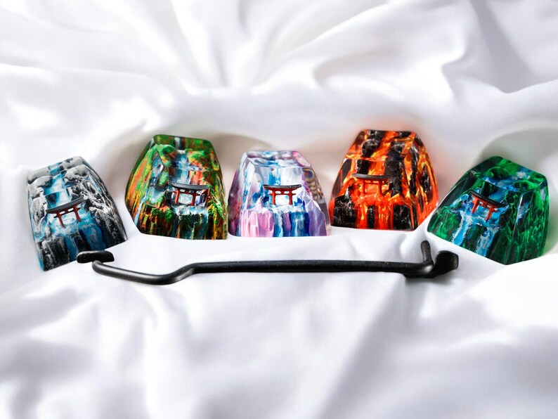 K&ouml;nnte beinhalten: F&uuml;nf bunte Harz-Keycaps mit einem japanischen Tempeldesign. Jede Keycap hat ein anderes Farbschema, darunter Blau, Gr&uuml;n, Lila, Orange und Schwarz.